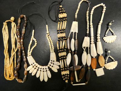 several different types of necklaces on a table with a black background