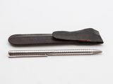 étui en cuir avec un stylo et un crayon posés sur une surface blanche