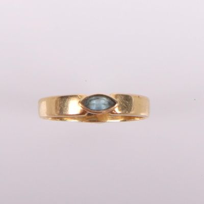 gros plan d'une bague en or avec une pierre bleue