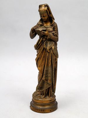 une statue en bronze représentant une femme tenant un livre dans ses mains