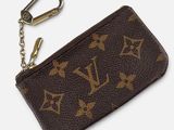 un gros plan sur un sac à main Louis Vuitton marron avec un porte-clés