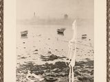 black and white photograph of a sailboat on a body of water with a lighthouse in the background