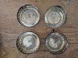 four silver plated dishes on a wooden table with a glass of water