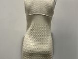 a white dress on a mannequin stand against a white wall