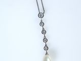 Un pendentif composé d'une perle blanche et de diamants est suspendu à une chaîne en argent