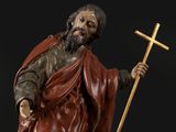 statue of a man holding a cross and a cross on top of a table