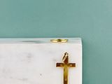 une croix en or posée sur un bloc de marbre blanc, posé sur une table