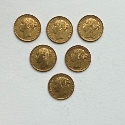six gold sovereigns are arranged in a triangle on a white surface