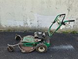 a small green lawn mower sitting on the pavement
