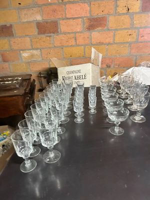 bottles and glasses are lined up on a table in front of a brick wall