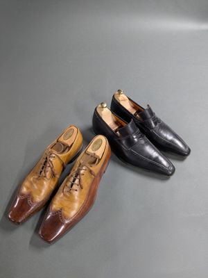 two pairs of brown and black shoes sitting on top of a table