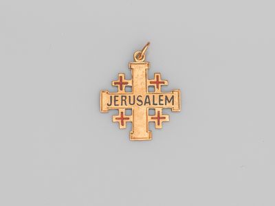 un pendentif en forme de croix en or sur lequel est gravé le mot « Jérusalem »