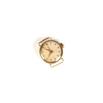 une petite montre en or posée sur une surface blanche, sur fond blanc