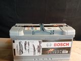 deux batteries Bosch posées sur une table en bois, sur fond noir