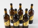 six bottles of wine are lined up in a row on a white surface