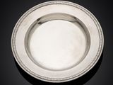 a silver plate on a black surface with a black background
