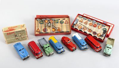 Il y a plusieurs petites voitures dans une boîte rouge et une boîte contenant des ciseaux