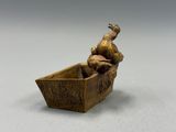 sculpture en bronze représentant un canard dans un bateau, posée sur une surface blanche