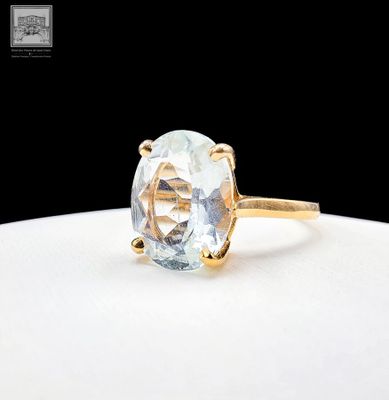 Gros plan sur une bague en or ornée d'une topaze bleue