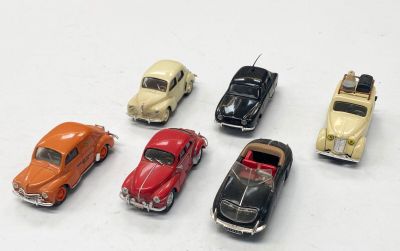 plusieurs petites voitures sont alignées sur une surface blanche