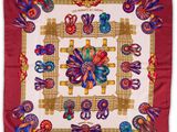 a red and white square scarf with colorful designs on it