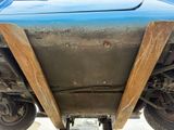 a blue truck with a wooden bumper underneath it