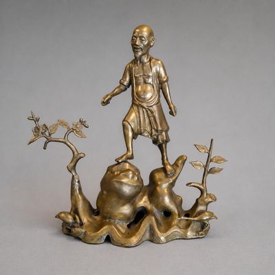 INDOCHINE Personnage debout sur un tertre rocheux. Bronze do…