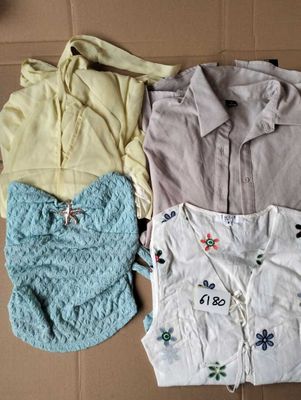 trois paires de chemises pour femmes et un bavoir pour bébé posés sur une boîte en carton