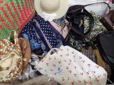 une pile de sacs à main et de chapeaux posée sur un lit