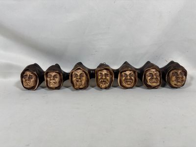 un ensemble de cinq têtes en bronze représentant des personnages, sur fond blanc