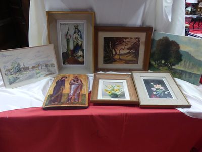 de nombreux tableaux encadrés posés sur une table recouverte d'une nappe rouge