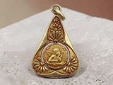 a close up of a gold pendant on a stone surface