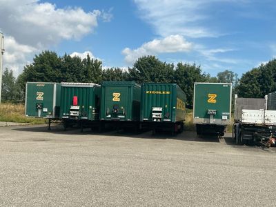 trois semi-remorques vertes garées sur un parking