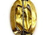 a gold brooch on a white surface with a knife