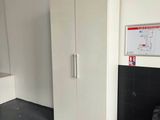 a white cabinet in the corner of a room with a black floor
