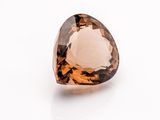 a close up of a faceted smokyite gemstone on a white surface