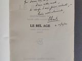 un livre ouvert, sur lequel est inscrit un poème manuscrit, posé sur une table