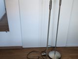two floor lamps on a wooden floor next to a mirror