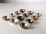 des bols plaqués argent disposés en cercle sur une surface blanche