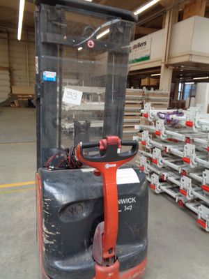 a fork lift truck in a warehouse with pallets of pallets in the background
