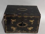 a black box with gold flowers on it on a white surface