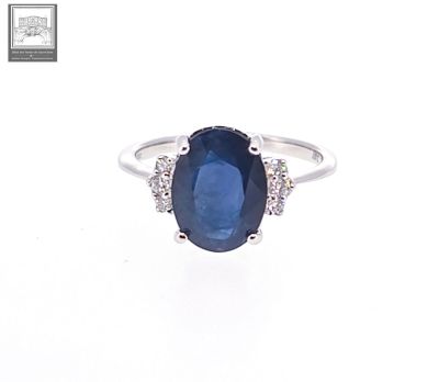 a close up of a ring with a sapphire and diamonds