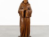 a wooden statue of a man holding a book in his hands