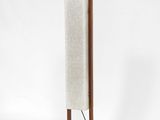 un grand lampadaire en bois muni d'un abat-jour en tissu blanc