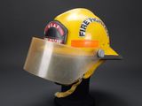 yellow firefighter helmet with visor on display against a black background