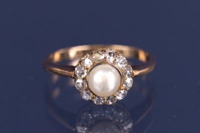 un gros plan d'une bague en perle et diamants posée sur un fond bleu