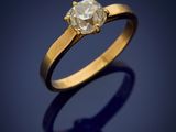 a gold ring with a white diamond on a dark background