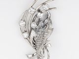 Gros plan sur une broche ornée de feuilles et de diamants sur fond blanc