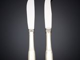 a pair of silver plated cheese knives on a black background