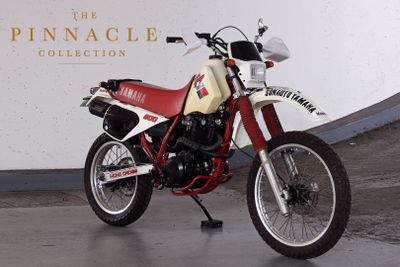 a red and white motorcycle parked in front of the pinnacle collection sign